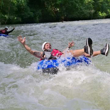 tourists in a raft with light blue tubes navigating white water rapids on the Savegre River, Costa Rica